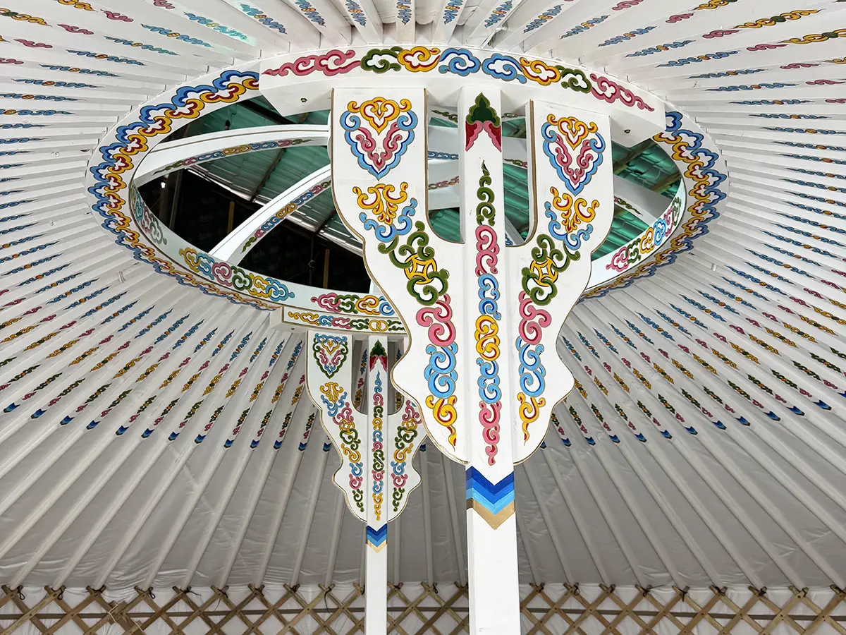 White interior of a Mongolian yurt showing two pillars with Mongolian traditional motif decoration