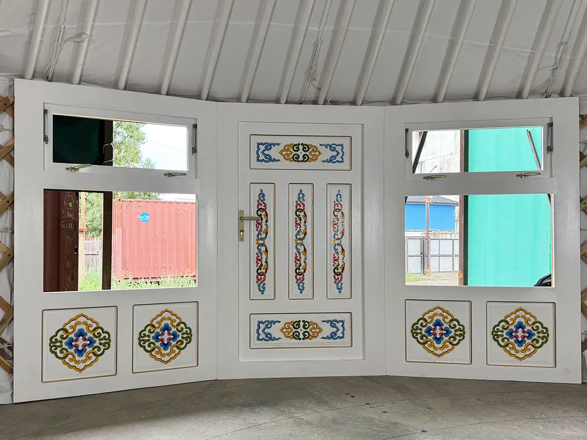 White interior of a Mongolian yurt showing two windows with a Mongolian traditional motif decoration