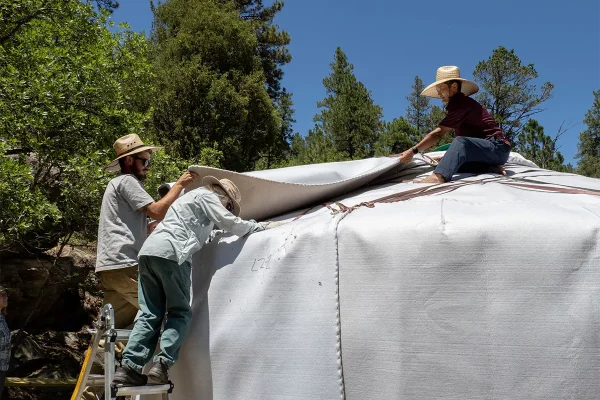 Placing roof felt three people placing roof felt on a Mongolian yurt